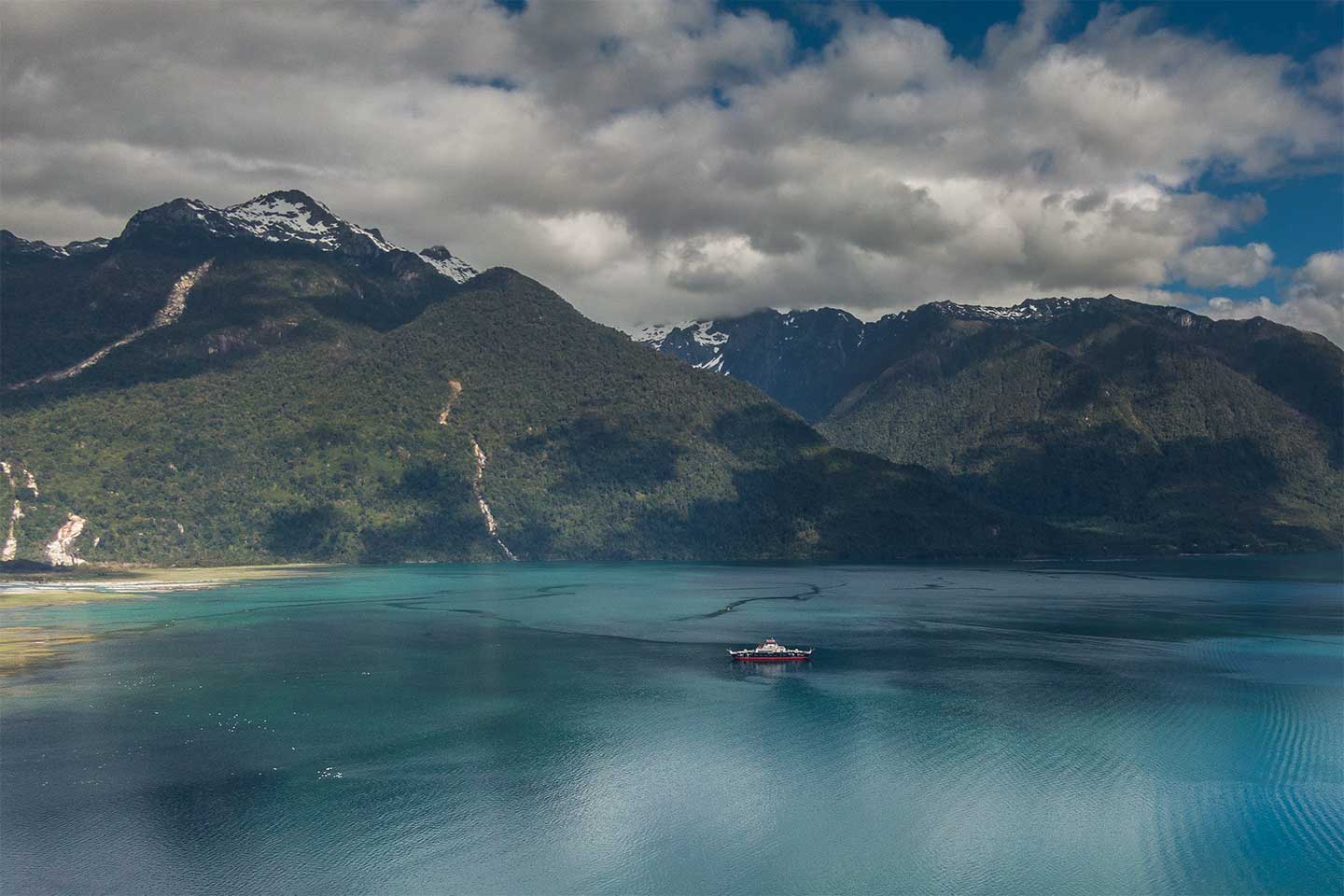 Blick über einen Fjord bei Hornopiren aus der Vogelperspektive. Im Fjord ifährt eine Fähre.