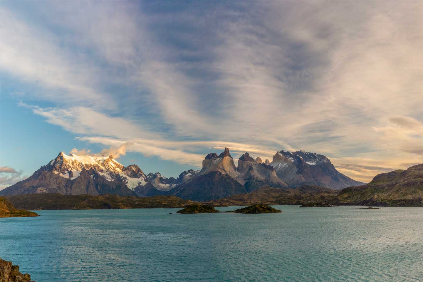 Panoramblick über eine Bergkette im Torres del Paine Nationalpark. Im Vordergrund ein Bergsee.