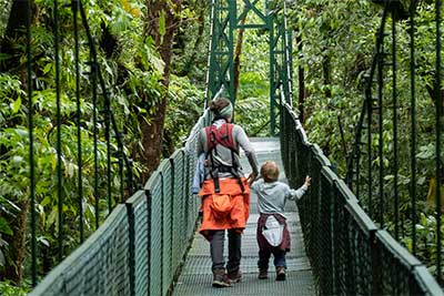 Zwei Menschen laufen über eine Hängebrücke im Monteverde Nebelwald