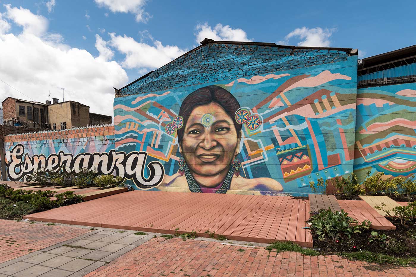 Auf einer Hauswand in Bogotá ist ein großes Graffiti-Gemälde mit einem großen Gesicht einer lachenden Frau