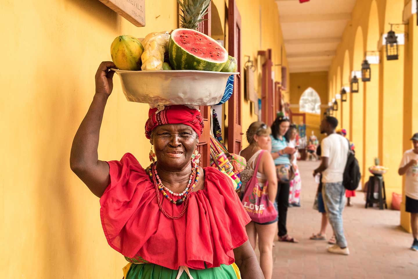 Eine Frau in Cartagena, die eine Schüssel mit Melone und Bananen auf de,m Kopf trägt